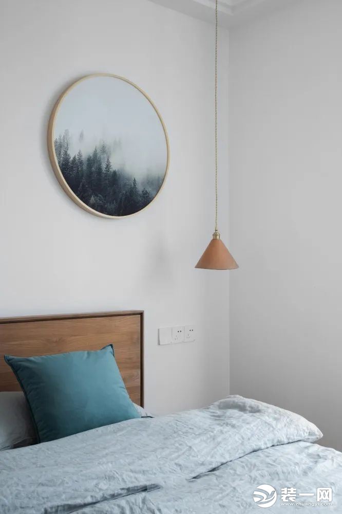 主卧室选用的是一张榆木的床，搭配素色的床品，干净切有质感，墙面上用一副圆形的云雾山装饰画，让卧室看上