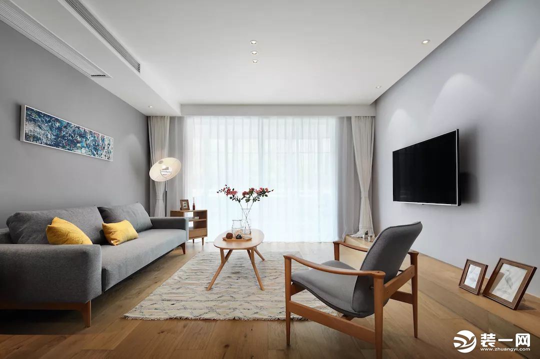 客厅以灰色背景墙为基调，打造时尚简洁的空间。木质地板和家具的融入，让家看起来自然又温馨。