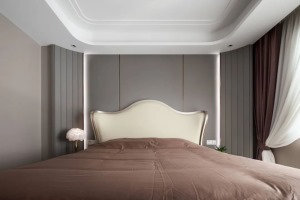 卧室床头墙以灰色护墙板的设计，床头两侧以软包材质做成斜角的设计，并在床头墙加入暗藏灯带与金属条，布置