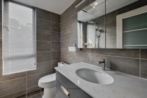 卫生间在灰色的地面墙面空间基础，窗户装上百叶帘让空间私密而明亮，结合定制洗手盆与镜柜，也让卫浴空间显