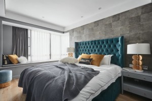 卧室床头墙贴上灰色仿古砖材质的背景墙，布置一张宝蓝色的皮艺床，布置灰白配的床单，两侧还有灰色的床头柜