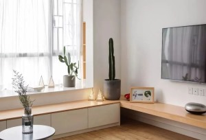 电视柜设计极为简约，长方形原木色搁板直接与飘窗卡座连成一体，原木色加白色的经典搭配，在绿色植物的点缀