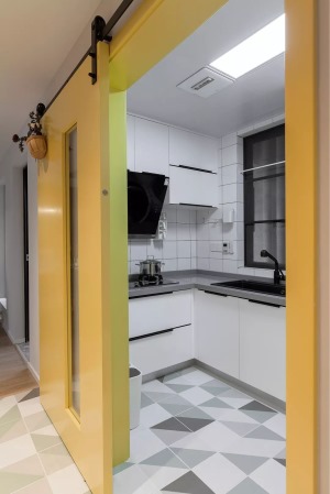在黄色的谷仓门后是厨房，U字形的操作台，整体白色的墙面与橱柜，结合灰色的操作台，整个现代简洁而时尚。