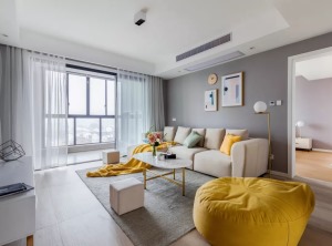 沙发墙的抽象几何挂画、还有时钟，让灰色调的背景墙显得更加艺术气质；米白色布艺沙发，搭配上鲜艳的黄色懒