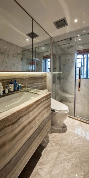 主卧卫生间的洗手盆柜与墙面保持统一纹理的设计，结合大尺寸的吊柜，还有干净时尚的淋浴房，让空间充满现代