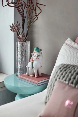 床头柜布置玻璃花瓶，插上干花，书籍上摆着一个妩媚的猫咪装饰，也增添了空间的浪漫与情趣氛围。