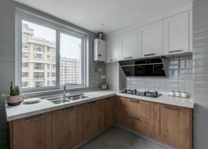 厨房在灰色六边砖的地面基础，墙面是白色的面包砖，结合木色橱柜与白色吊柜，L形的操作台空间，让做饭的氛