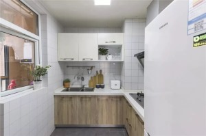 厨房呈L型布局，墙面铺白色小方砖，地面铺贴水泥砖，原木橱柜配上白色吊柜，这样更显空间层次感。各种小绿