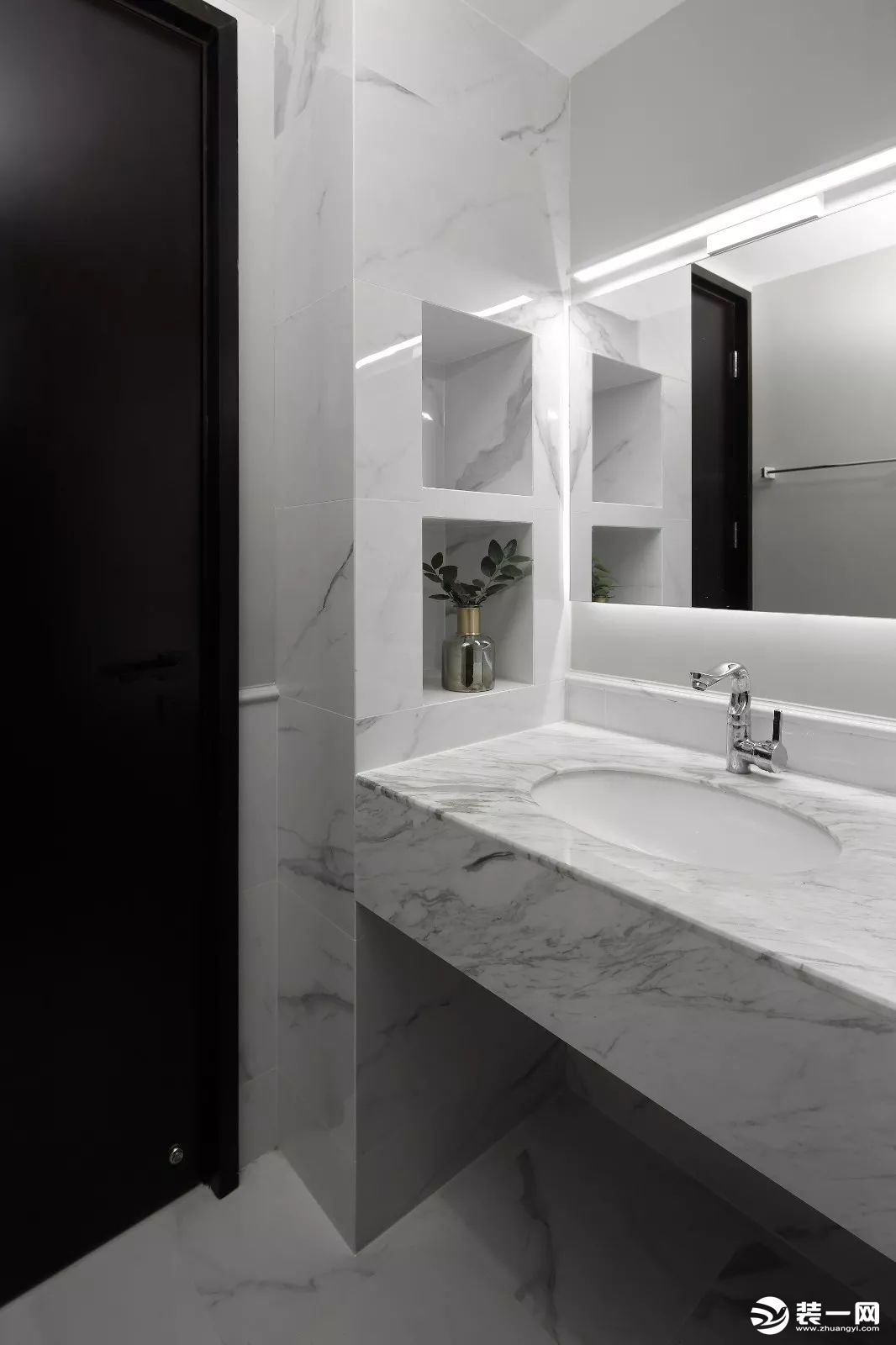 卫生间内部是选择了更为明亮、大气的爵士白大理石瓷砖，在浴室镜的上方安装一条灯带，让卫生间看起来更加宽