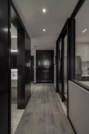 入户是门厅和走廊相结合的空间，黑色的柜子、门框搭配白色的墙面和灰色的木地板，从一进门就展现出整体黑白