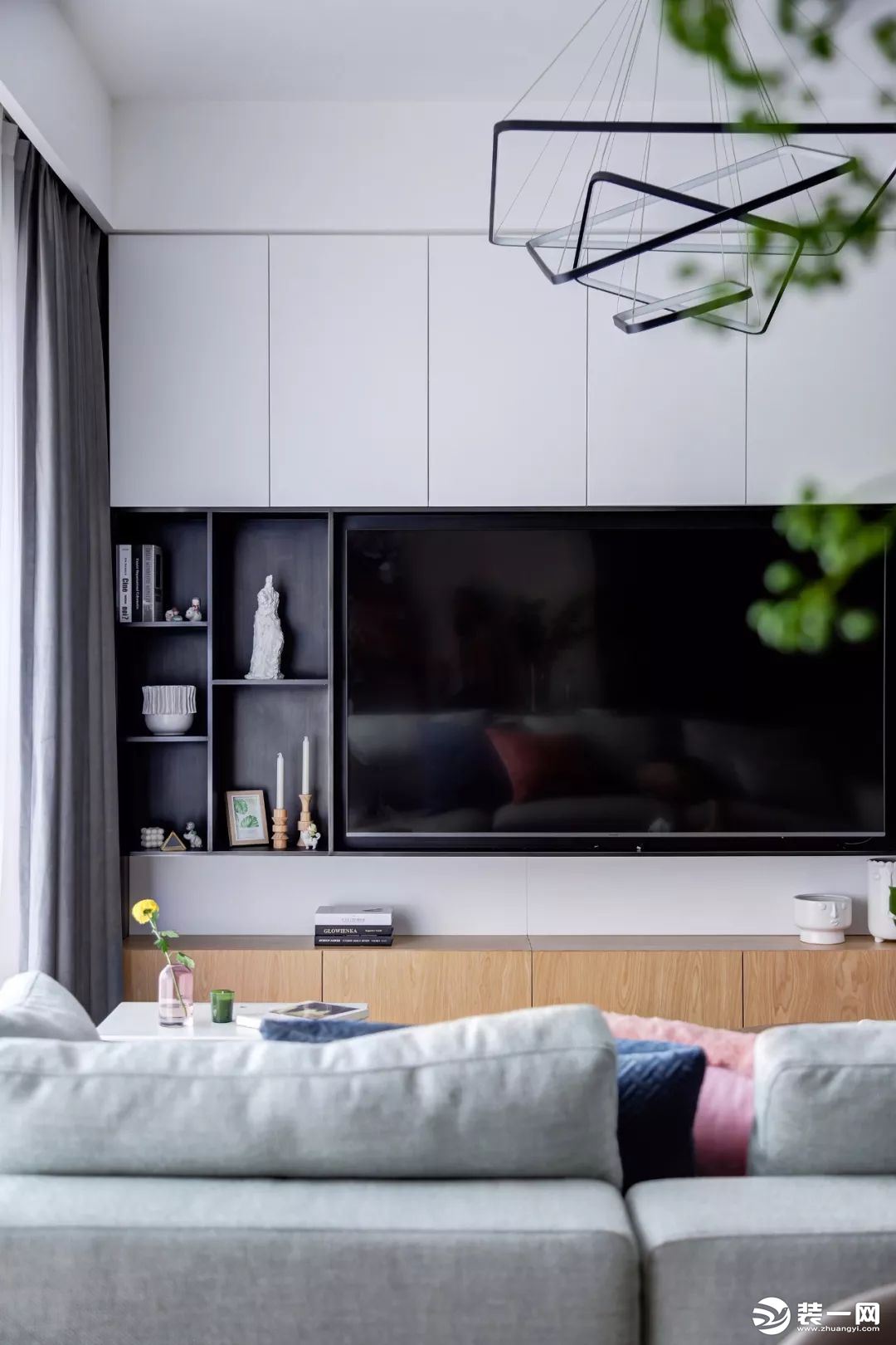 电视墙以定制柜作为主体，左侧加入了几个黑色的开放格架，摆上雅致的装饰品，让空间显得现代优雅而大气。