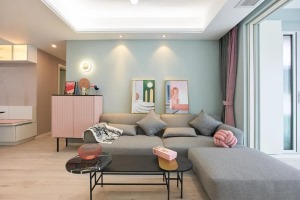 客厅草绿色墙面富有生机与活力，L型沙发舒适又实用，浅灰色降低了客厅整体的色彩饱和度。