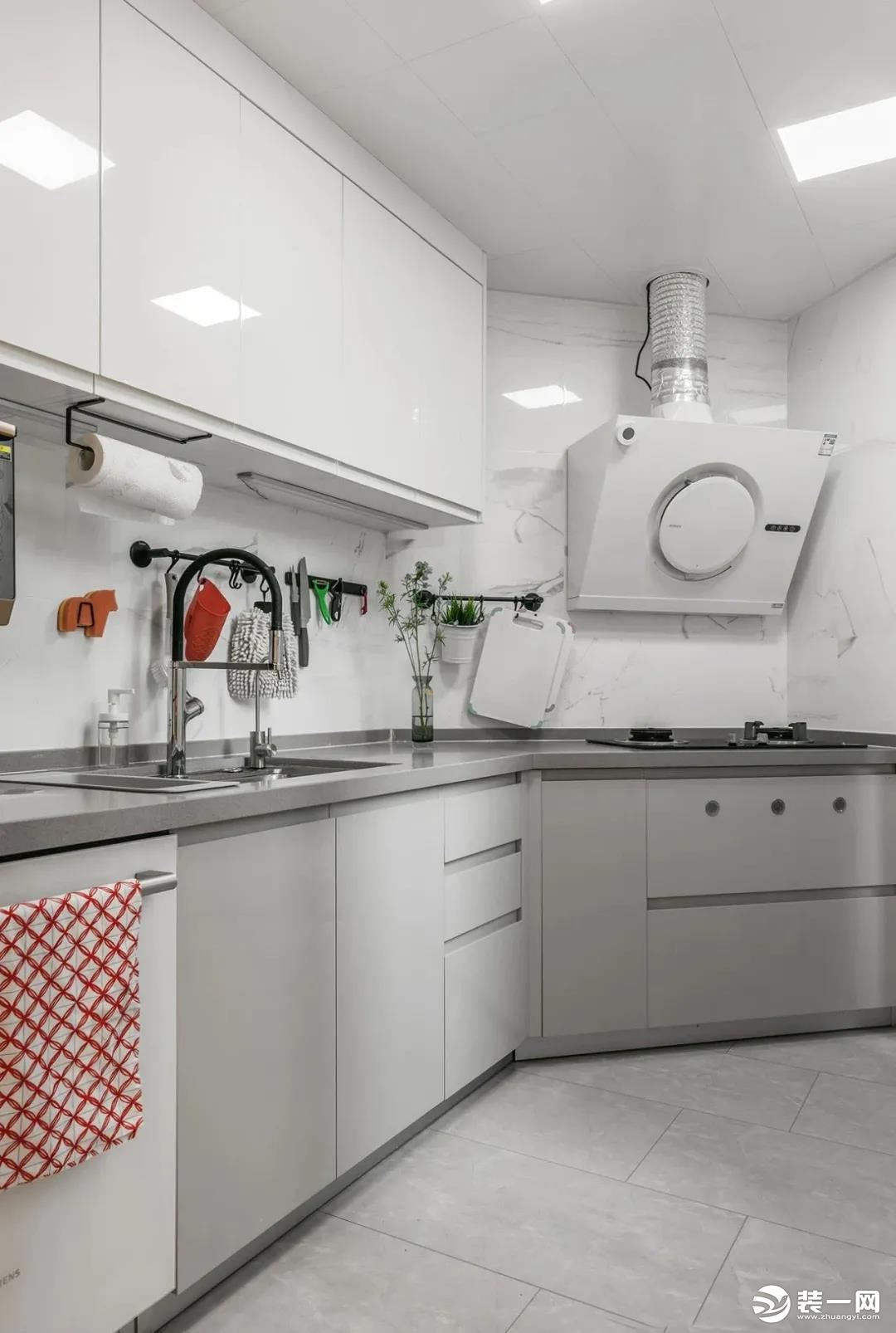 将不规则的无窗厨房打造成白灰色系，灯光下整个空间明亮起来，哑光地砖柔和，吊柜底部安装灯管，避免切菜时