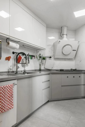 将不规则的无窗厨房打造成白灰色系，灯光下整个空间明亮起来，哑光地砖柔和，吊柜底部安装灯管，避免切菜时