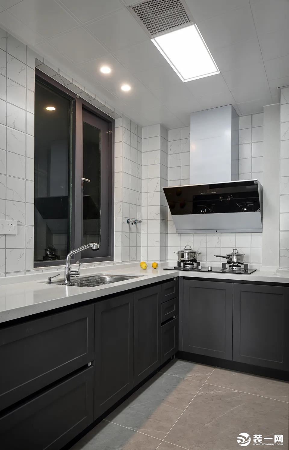 厨房在灰色地面砖的基础，墙面则是小白砖，而深灰色的橱柜设计，搭配在这个现代大方的厨房空间里，也是显得