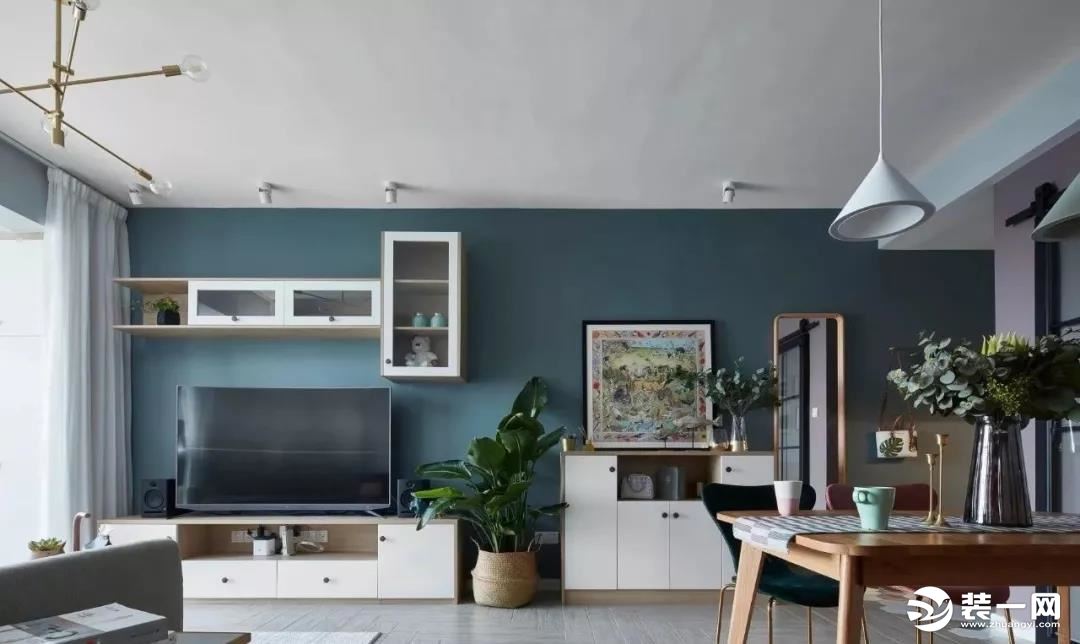 客厅的电视墙背景色与玄关的灰蓝色保持一致，电视柜旁边一盆绿植，结合白色的电视柜与吊柜，带来了一个清新