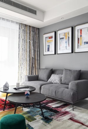 黑色的茶几，以圆形双拼的组合，搭配上素雅的灰色沙发，沙发墙后方的挂画有着简约图案+鲜艳的配色，在简约