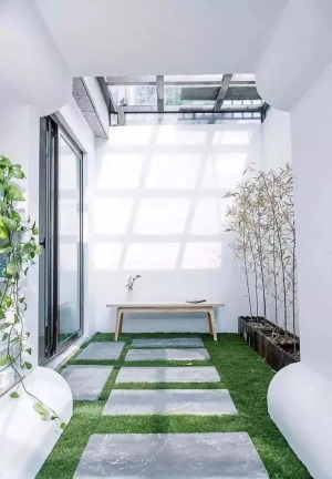 负一层的采光井封了一个玻璃顶，形成一个室内小花园的空间，绿色草坪加上青石板，旁边种着小青竹，温暖的阳