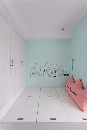 另外一間臥室是被做成了榻榻米床組合衣柜的款式，墻面刷成了清新的藍綠色，搭配粉色的軟裝和可愛的墻貼，讓