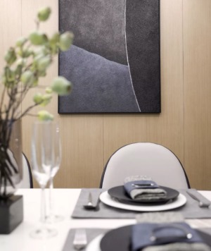 而餐厅的另一侧墙面是铺上了木饰板，搭配灰色调的装饰画、大理石的餐桌和简洁的餐椅。