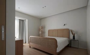 卧室没有多余的装饰，基调以灰色和原木色为主，柔和的藤编双人床和边柜搭配干枝芦苇花多了一分静谧和禅意。