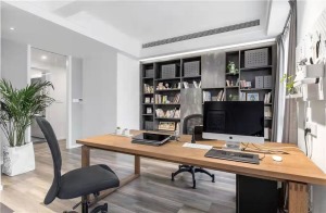 墙面定制的开放性式灰色书架，摆上主人的藏书，结合木质的书架，让办公氛围显得简约舒适而自然