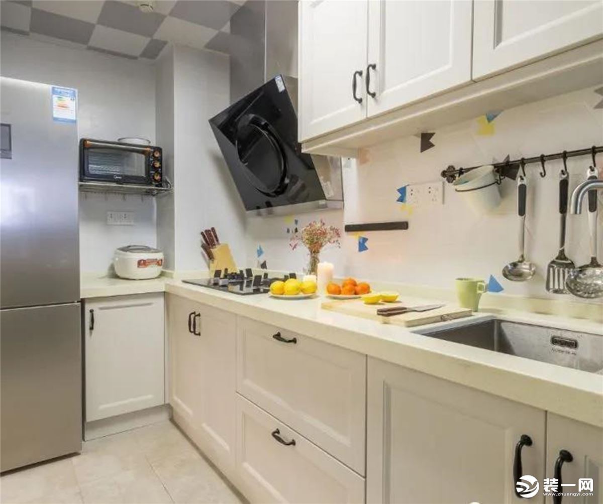 L型厨房的布局，暖色瓷砖搭配白色模压橱柜，可以满足日常收纳。镶嵌在角落里的冰箱充分利用了空间布局，