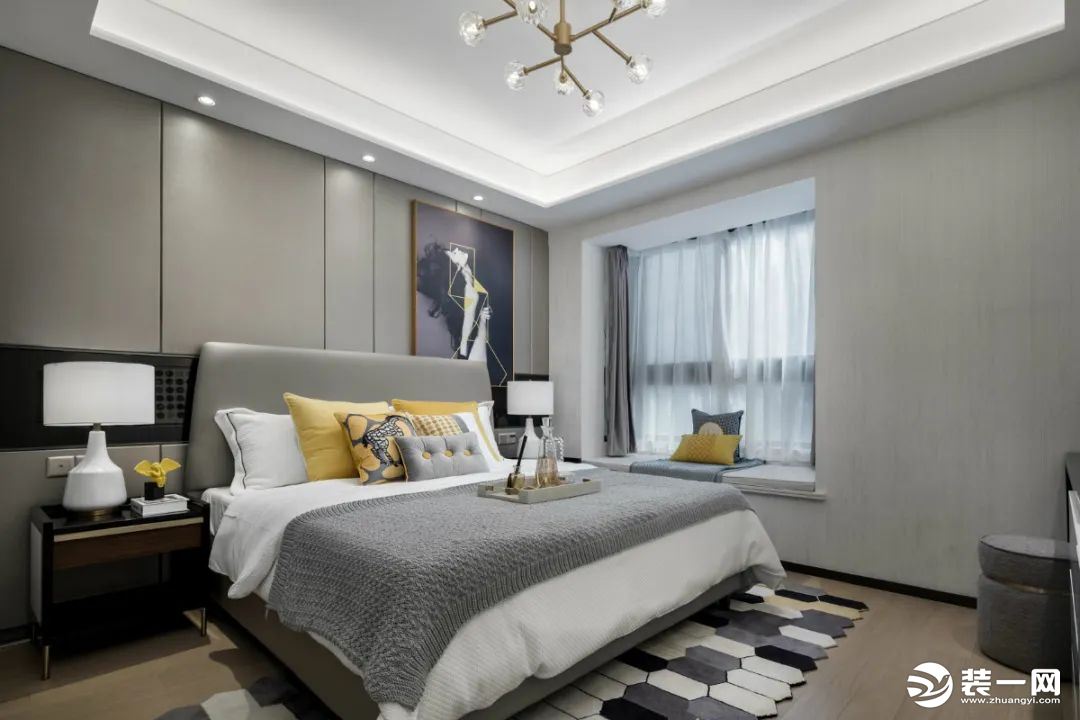 卧室整个空间以灰色调为主，在床头墙装上灰色护墙板，摆上一张灰色皮艺床，布置灰白配的床单，加上黄色的枕