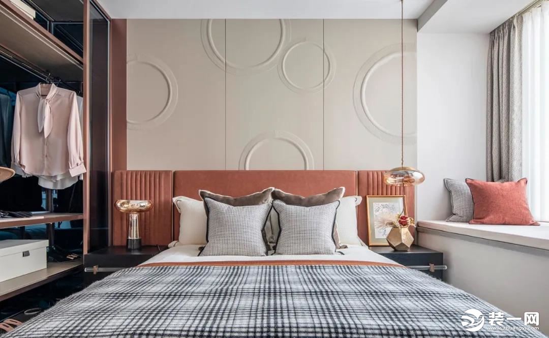 主卧整体收纳与使用功能强大，圆形钢印式图案的背景墙简约又有线条感，搭配橙红色的床头靠背，美感十足。