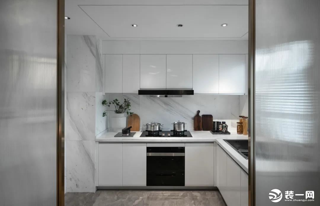 厨房地面保持与客餐厅一致的质感，墙面加入雅白的墙砖，装上白色的定制橱柜，让做饭空间也干净优雅而情趣。