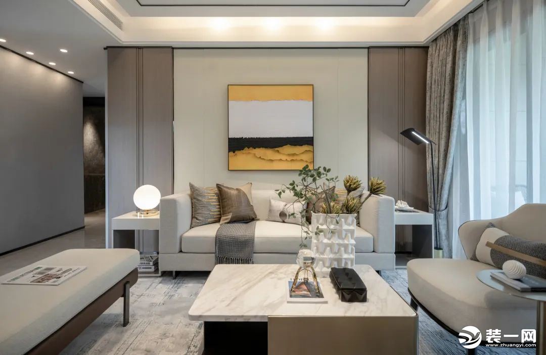 现代风的客厅，整个空间都以卡其色的调调，沙发墙挂上一幅色彩冲击明显的装饰画，布置米白色皮沙发，而电视