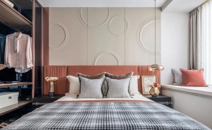 主卧整体收纳与使用功能强大，圆形钢印式图案的背景墙简约又有线条感，搭配橙红色的床头靠背，美感十足。