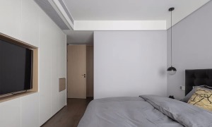 卧室整体灰色的墙面空间，搭配灰色的床单，床尾整面墙都做成定制柜，并在中间加入了电视机的空格位，为卧室