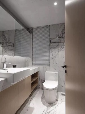 卫生间在雅白的墙面地面基础，洗手台台面做窄保留宽松的动线与马桶区域，装上一个半入台的洗手盆，为主人提