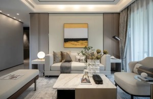 现代风的客厅，整个空间都以卡其色的调调，沙发墙挂上一幅色彩冲击明显的装饰画，布置米白色皮沙发，而电视