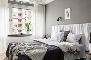 卧室;一张双人床，宽敞明亮，清晰看到绿色的盆栽，全屋灰白色彩，白色窗帘，有一股睡意不由而生