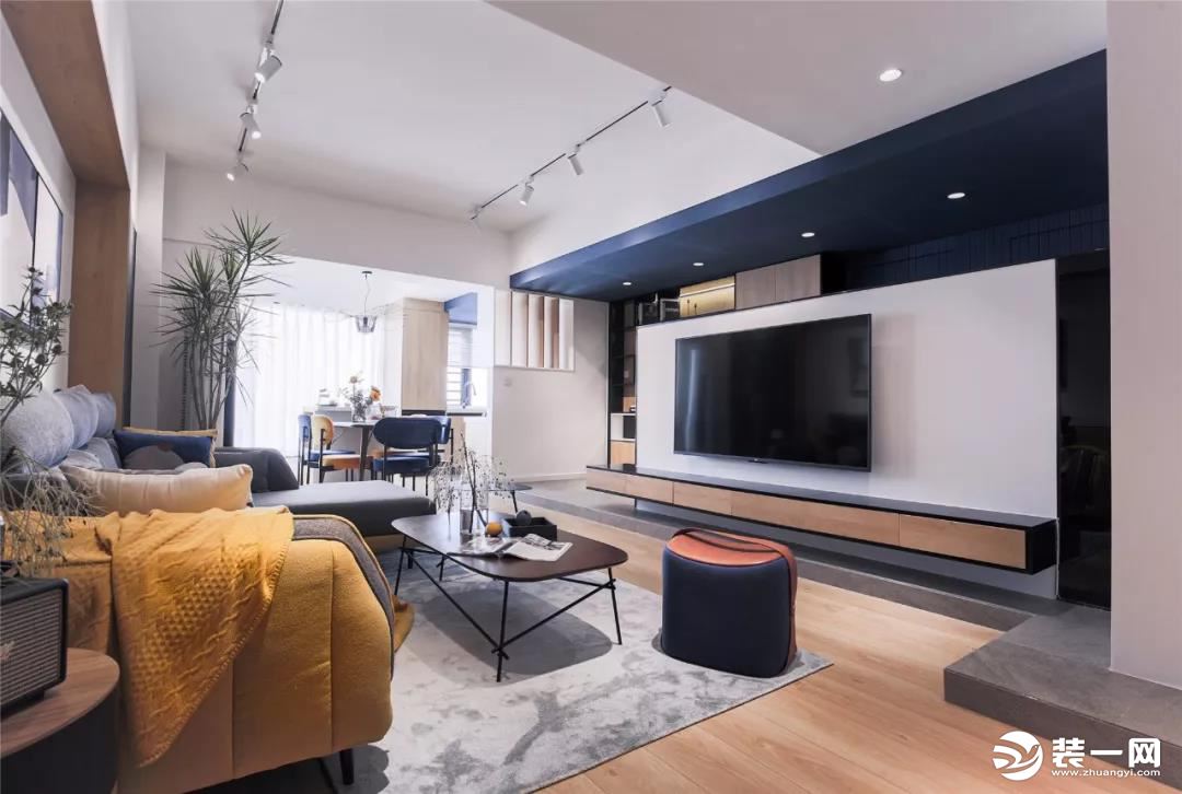 客厅整体现代大方的空间，电视墙在蓝白配的设计下，把蓝色延伸到天花的筒灯下，地台+定制的离地电视柜，让