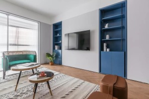 客厅取消了电视柜，采用电视机直接壁挂上墙，内嵌式蓝色储物柜特意设计成对称样式，平衡整个区域的重心。