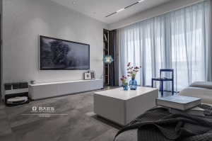客厅的装饰以灰白色为主，辅以沉稳的蓝色，再加上落地灯以及各材质营造出的质感，整体的布局简洁大气。