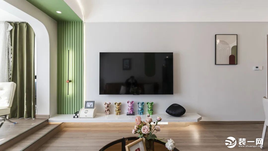 电视背景墙以浅灰色填充，小型装饰画上墙，家具轻量化，让空间尽显透彻。悬空地台下方嵌入氛围灯带，与格栅