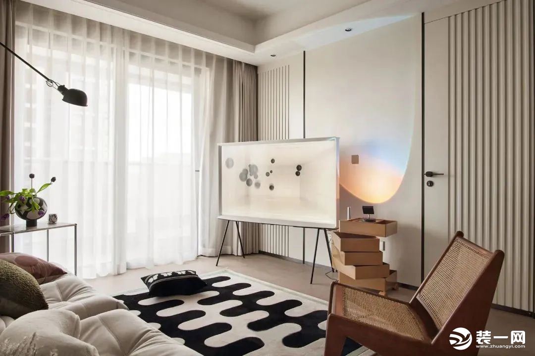 奶油色铺陈的背景墙面，以独特的边框线条彰显出空间的层次感，选择可移动电视支架满足空间灵活性，角落的彩