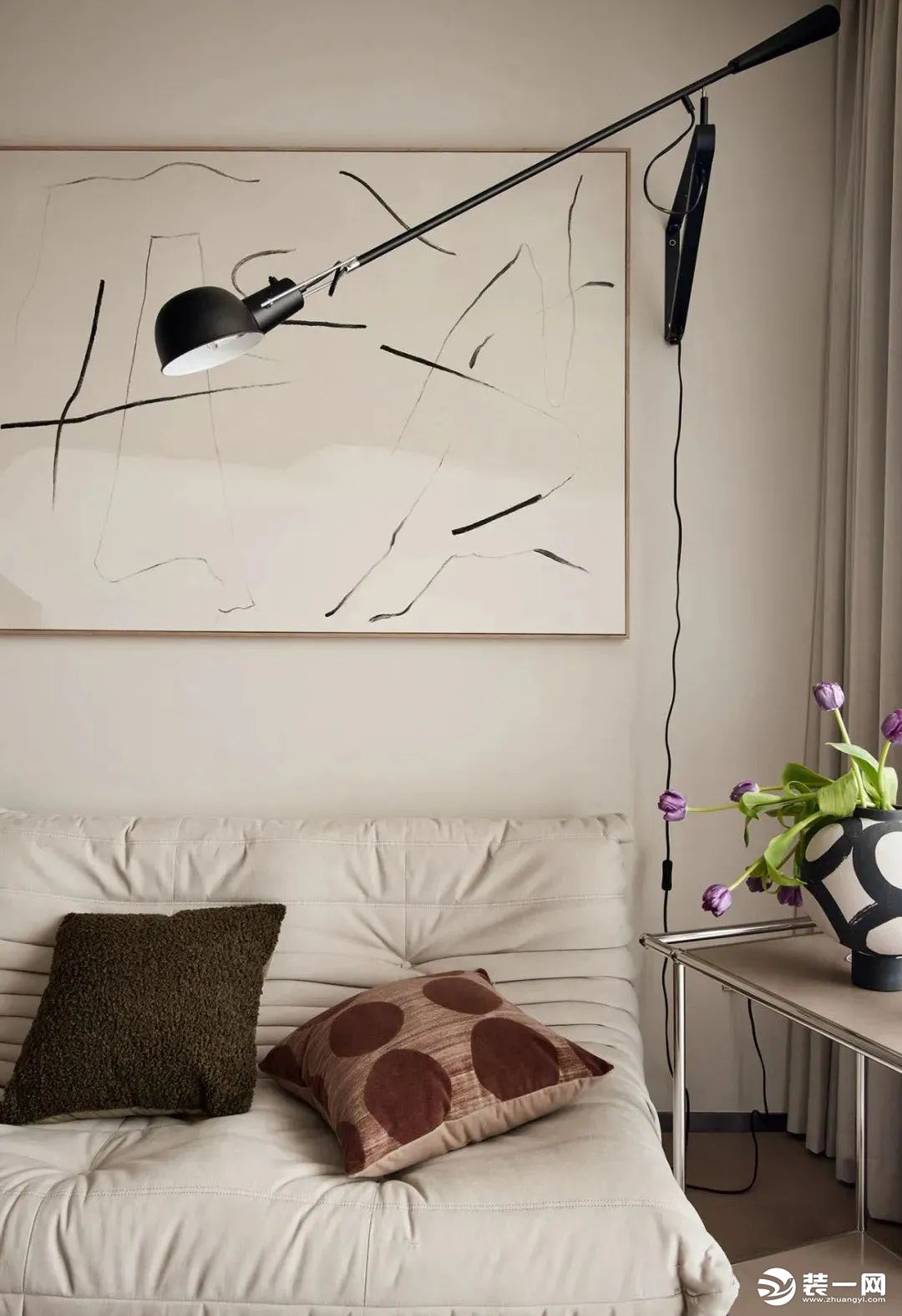 沙发背景墙留白处理，以一副抽象挂画简单装饰，搭配一盏黑色金属落地灯，抱枕点缀空间色彩，提升客厅空间的