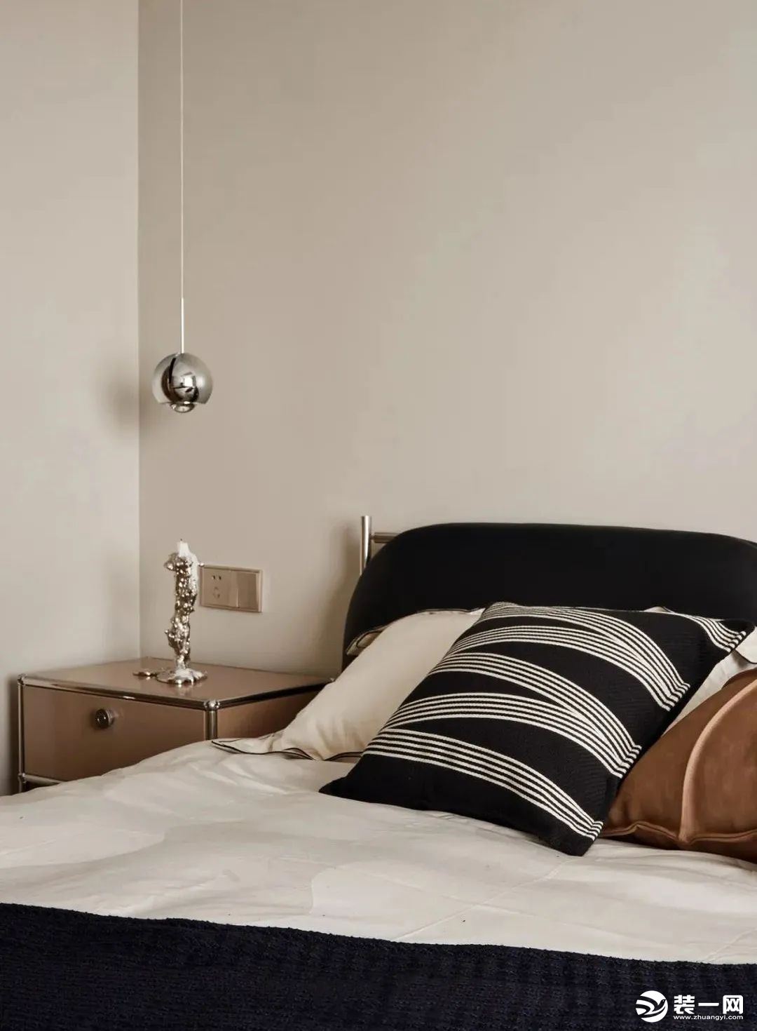 床品搭配黑白基础色调，原木质感的床头柜，加以银饰边框勾勒，和床头的小圆吊灯相呼应，简单的陈设浸润出静
