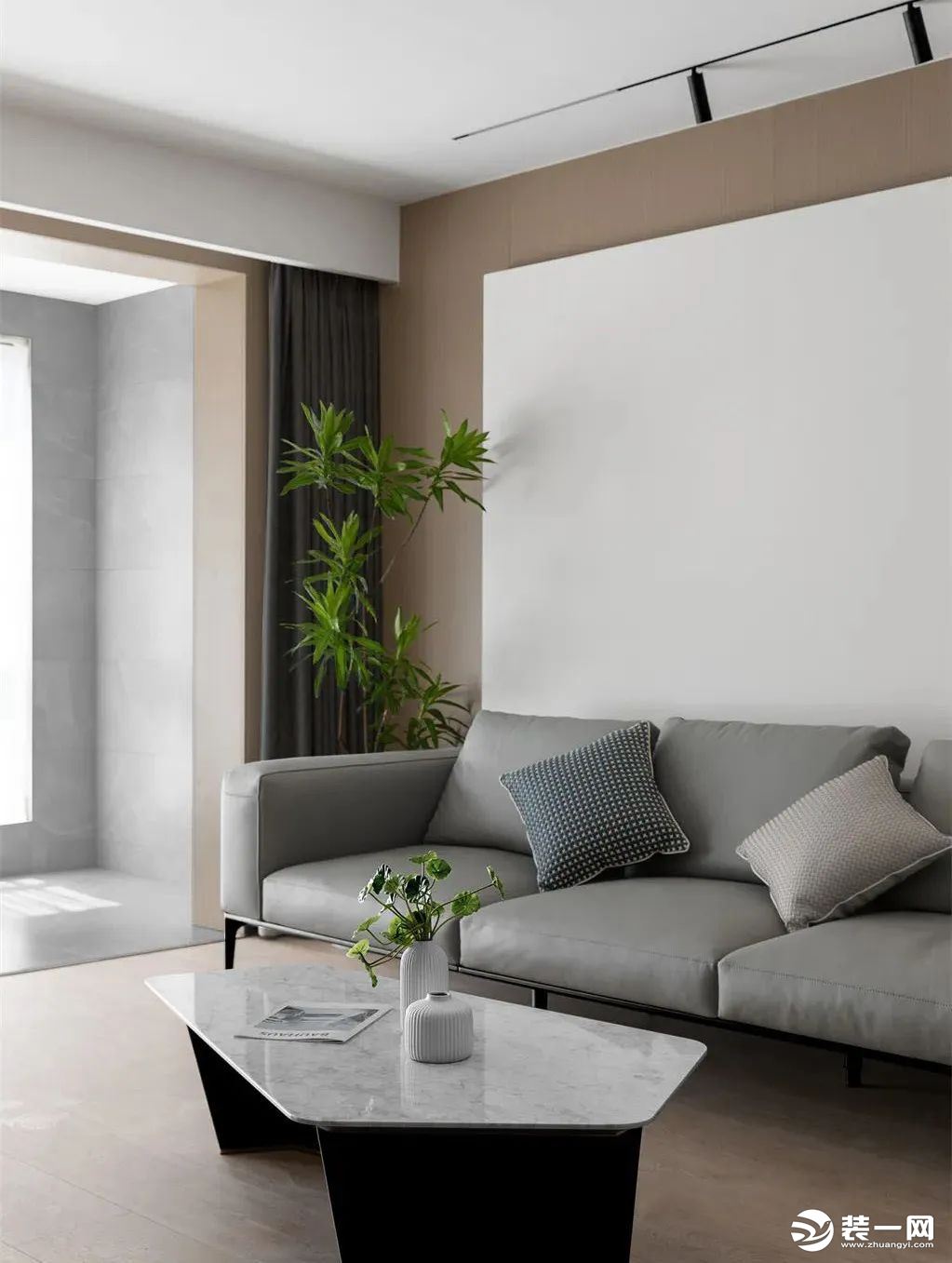 软装以灰色皮艺材质的沙发布置，搭配大理石纹异形茶几，背景墙以原木色和纯白色进行拼色设计，营造出简约又