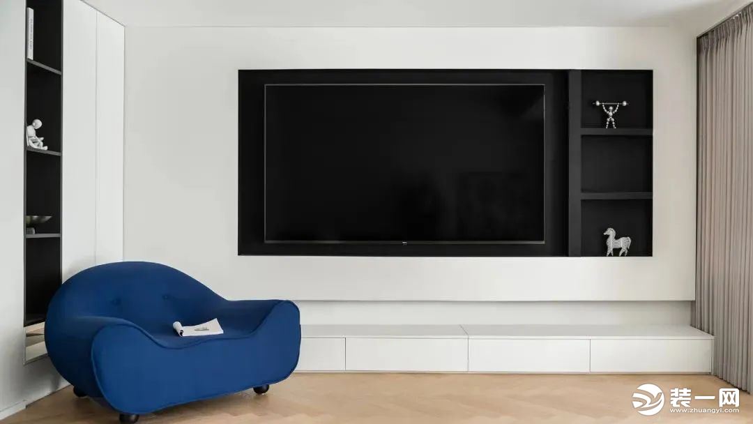 电视背景墙延续白色为基底，中间黑色凸显层次感，一侧增加通顶开放柜，为收纳空间扩容，一抹克莱因蓝亮色点