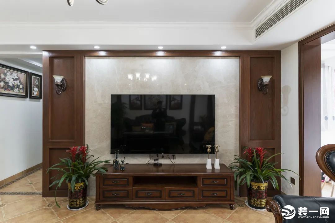 电视背景墙左右两侧对称布局，以木饰面装饰。深胡桃木的电视柜，与餐桌，茶几同款材质，各个空间彼此独立又
