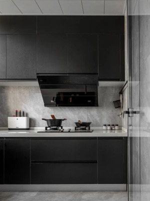 厨房，采用透明玻璃门隔断，以灰色大理石瓷砖铺贴墙地面，白色台面搭配黑色橱柜，营造现代感十足的整体氛围