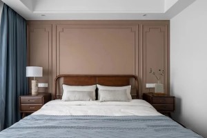 床头背景选择奶咖色艺术漆，两侧布置对称胡桃木床头柜，家具简单而质感，沉稳的木色平衡了空间的暖色调，达