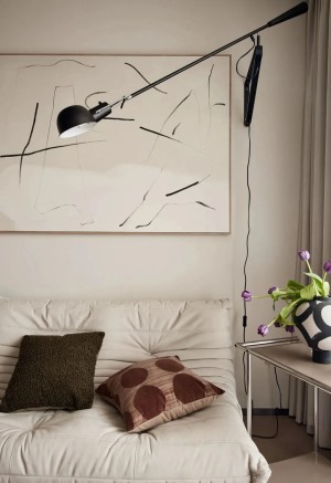 沙发背景墙留白处理，以一副抽象挂画简单装饰，搭配一盏黑色金属落地灯，抱枕点缀空间色彩，提升客厅空间的