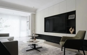 电视背景墙与储物柜融为一体设计，白色柜门搭配呈现出干净整洁的视觉，电视机旁设计开放式柜体，阳台处弧形